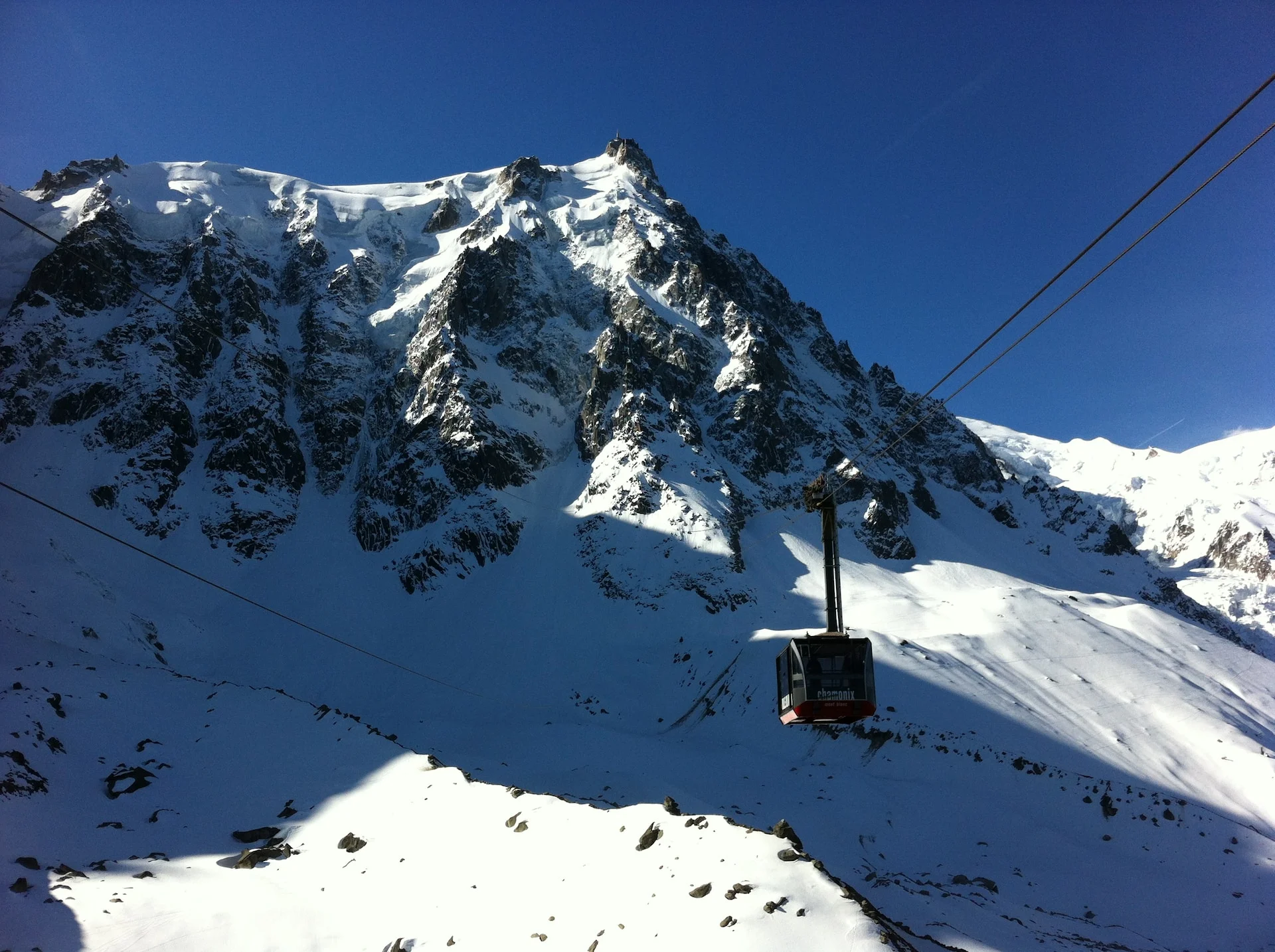 black cable car over snow covered mountainnder a blue sky