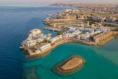 Hurghada Red Sea coast with luxury beach resorts, turquoise waters, coral reefs, traditional Egyptian boats, desert mountains in background, water sports and diving activities