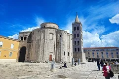 Zadar Sea Organ steps creating music from waves, Sun Salutation solar-powered light circle at sunset, Roman Forum ancient stone ruins, St. Donatus circular church, Adriatic sunset golden sky, Kornati Islands archipelago, medieval city walls and gate, Maraschino cherry liqueur, traditional Dalmatian architecture, ferry boats