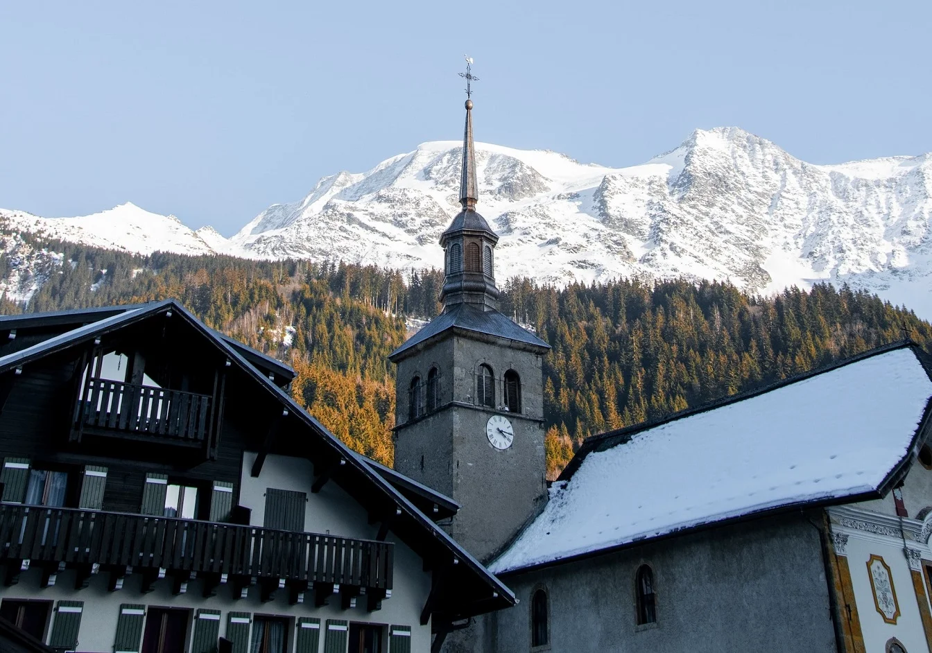 a building with a steeple in front of a snowy mountain