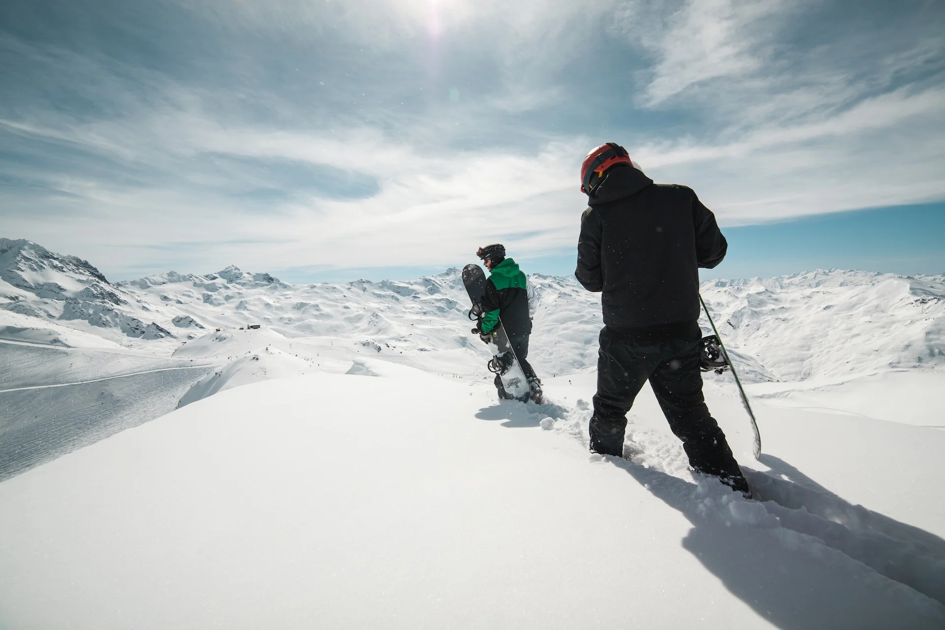 two people carrying snowboards on snow covered terrain